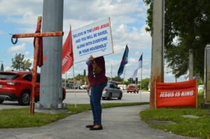 Woman holding Jesus sign on city sidewalk for faith and evangelism.