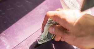 A hand placing a dollar into a donation box outdoors, symbolizing generosity and charity.